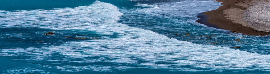 horizontal shot of  blue waves on the beach making an s line with brown sand