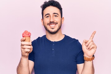Young hispanic man holding ice cream smiling happy pointing with hand and finger to the side