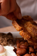Primer plano de mano de hombre comiendo chicharron de cerdo frito. Comida tradicional colombiana