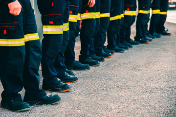 Many unrecognizable firefighters lined up in reflective pants.
