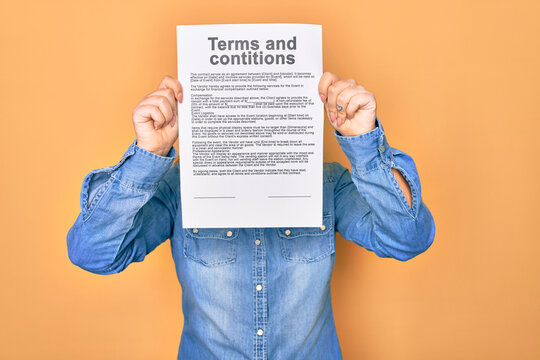 Woman holding terms and conditions document paper standing over isolated yellow background