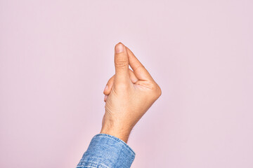 Hand of caucasian young man showing fingers over isolated pink background holding blank space with thumb finger, business and advertising