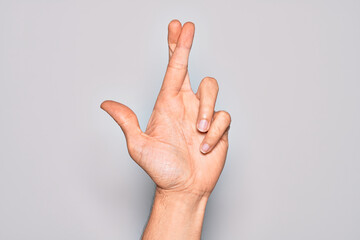 Hand of caucasian young man showing fingers over isolated white background gesturing fingers crossed, superstition and lucky gesture, lucky and hope expression