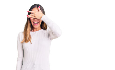 Obraz premium Beautiful brunette young woman wearing casual white sweater and glasses smiling and laughing with hand on face covering eyes for surprise. blind concept.