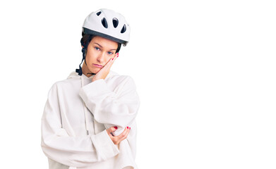 Beautiful brunette young woman wearing bike helmet and sporty clothes thinking looking tired and bored with depression problems with crossed arms.