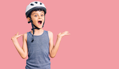 Little cute boy kid wearing bike helmet celebrating victory with happy smile and winner expression with raised hands