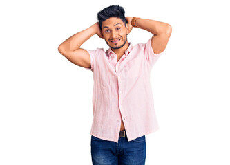 Fototapeta premium Handsome latin american young man wearing casual summer shirt relaxing and stretching, arms and hands behind head and neck smiling happy