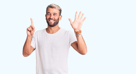 Fototapeta premium Young handsome blond man wearing casual t-shirt showing and pointing up with fingers number six while smiling confident and happy.