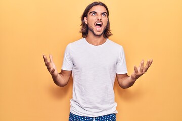 Young handsome man wearing casual clothes crazy and mad shouting and yelling with aggressive...