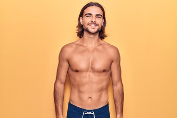 Fototapeta premium Young handsome man wearing swimwear shirtless with a happy and cool smile on face. lucky person.
