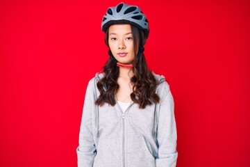 Young beautiful chinese girl wearing bike helmet with serious expression on face. simple and natural looking at the camera.