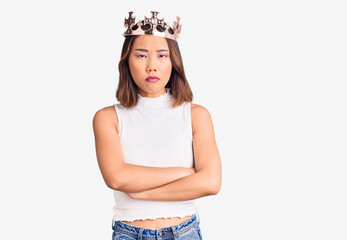 Young beautiful chinese girl wearing princess crown skeptic and nervous, disapproving expression on...