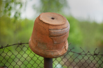 Naklejka premium A clay pot hangs on the fence. Old dishes.