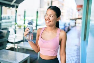Young beautiful hispanic sporty woman wearing fitness outfit smiling happy and natural at the town...