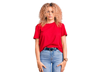 Young blonde woman with curly hair wearing casual red tshirt skeptic and nervous, frowning upset because of problem. negative person.