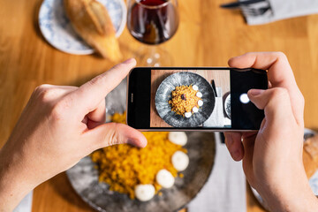 Man hand with smartphone photographing food at restaurant or cafe. High quality photo