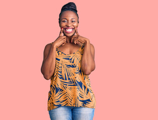 Young african american woman wearing casual clothes smiling with open mouth, fingers pointing and forcing cheerful smile