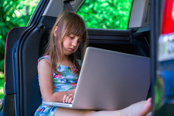 Learn аlways and everywhere. Young beautiful girl sitting in the car and using laptop.