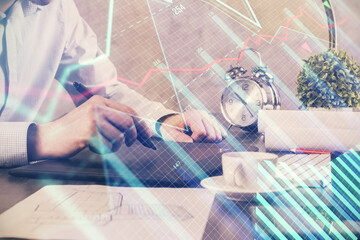 Double exposure of man's hands holding and using a phone and financial graph drawing. Analysis concept.