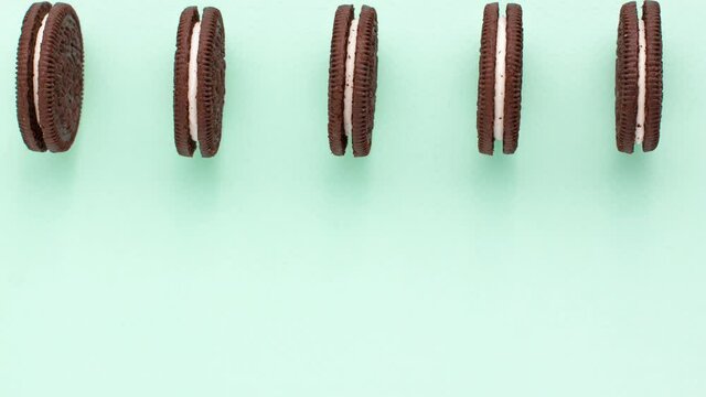 Sweet brown cookies with white cream inside move back and forth on bright blue background on the top. Stop motion animation close up with copy space. Homemade and bakery concept