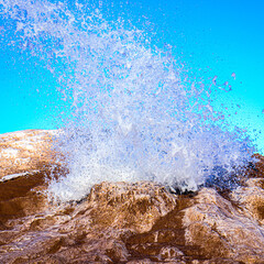 Water exploding from ice covered in sand