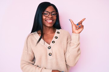 Young african american woman wearing casual clothes smiling cheerful pointing with hand and finger up to the side