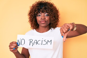 Young african american woman holding no racism banner with angry face, negative sign showing...