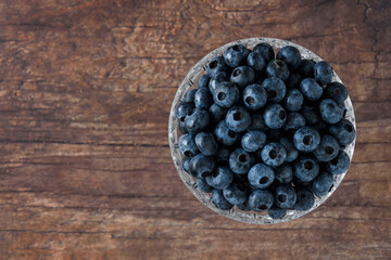 Top view of fresh blueberries in a crystal bowl on a rustic wood table
