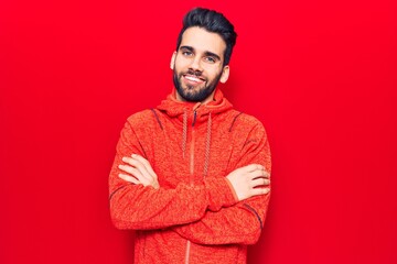 Young handsome man with beard wearing casual sweatshirt happy face smiling with crossed arms looking at the camera. positive person.