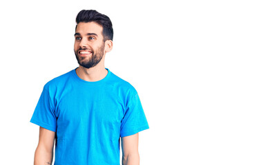 Fototapeta premium Young handsome man with beard wearing casual t-shirt looking away to side with smile on face, natural expression. laughing confident.