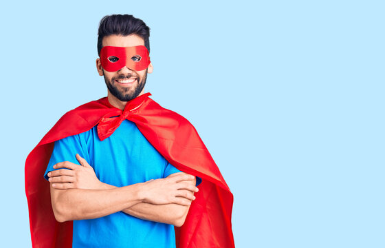 Young handsome man with beard wearing super hero costume happy face smiling with crossed arms looking at the camera. positive person.