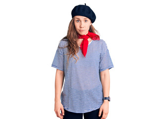 Young beautiful blonde woman wearing french beret and striped t-shirt skeptic and nervous, frowning...