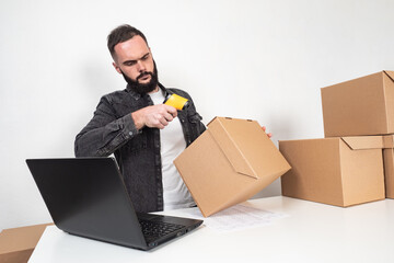 Man using barcode reader on a box in a warehouse. Marking boxes with the product. A man reads the bar codes from the boxes. Storekeeper with a barcode reader next to cardboard boxes.