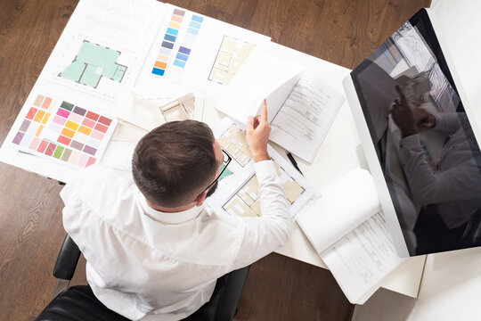 A Man Makes An Estimate Of Construction Work. Calculating The Cost Of A New Home. Construction Engineer At His Desk. Work On A Construction Project.