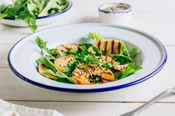 Grilled Halloumi Cheese salad with peach and arugula on a white wooden background. Healthy food concept.