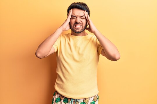 Young hispanic man wearing swimwear with hand on head, headache because stress. suffering migraine.