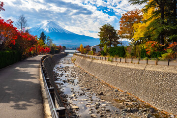 Japan. Fuji in the autumn. The shallow river flows into lake Kawaguchiko. Autumn landscape of Japan. Panorama Of Japan. Mount Fuji on the background of the river, autumn trees and clouds. Fujisan