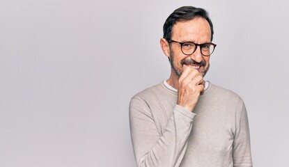 Middle age handsome man wearing casual sweater and glasses over isolated white background smiling looking confident at the camera with crossed arms and hand on chin. Thinking positive.