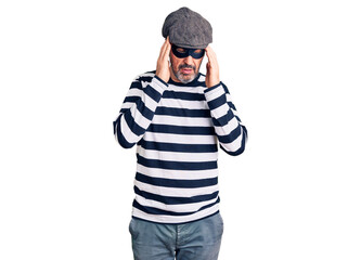 Middle age handsome man wearing burglar mask with hand on head for pain in head because stress. suffering migraine.