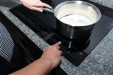Female hand turns on electric hob closeup