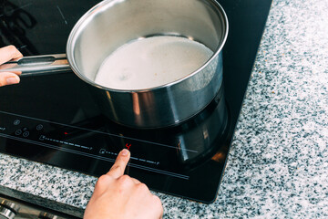 Female hand turns on electric hob closeup