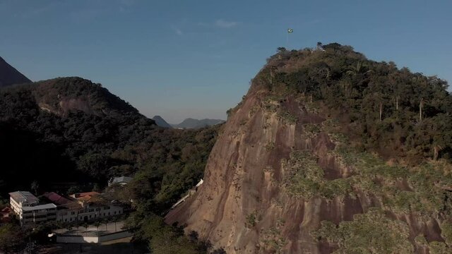Closeup aerial pan showing the Leme hill rock with Brazilian flag on top marking the fort revealing the Sugarloaf mountain in the background