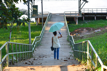 Girl with her umbrella to protect herself from the sun and enjoy the view of the Napo river Peru