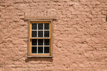 Fototapeta na wymiar Old wooden window set into the red birck wall of a house in a ghost town in Utah.