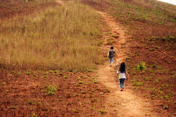 Brother and sister, Boy and girl  walking up to the hill.  Two kids walking up to the Phu Khao Ya (Grass hill) at Ranong province of Thailand.