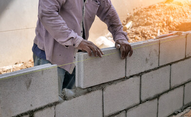 close up at the bricklayer hands, the builder puts the bricks at construction site
