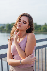 Pretty young woman posing on the old rusty transport bridge over the river during sunset.