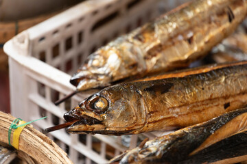 Vietnamese street food, smoked mackerel fish on a skewer in a Saigon market. 
