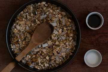 Granola in a round broiler on a wood table. Muesli. Top view