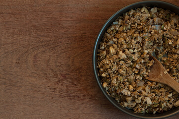 Granola in a round broiler on a wood table. Muesli. Top view